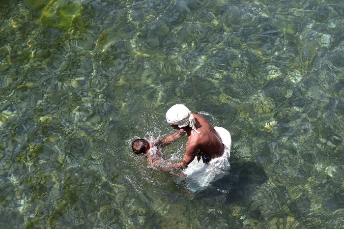 A Sikh pilgrim dips his son in Gurdwara Panja Sahib, a shrine of the Sikh community's spiritual saint, in Hasan Abdel, Pakistan (Farooq Naeem-AFP) (126K)